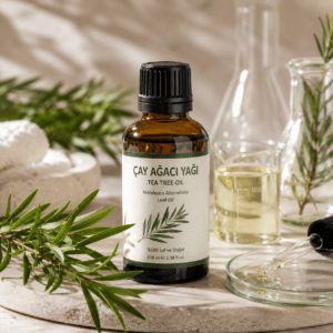 Çay Ağacı Yağı (Tea Tree Oil) amber cam şişede, Melaleuca alternifolia yaprakları ve laboratuvar ekipmanları ile doğal kozmetik hammadde görseli.